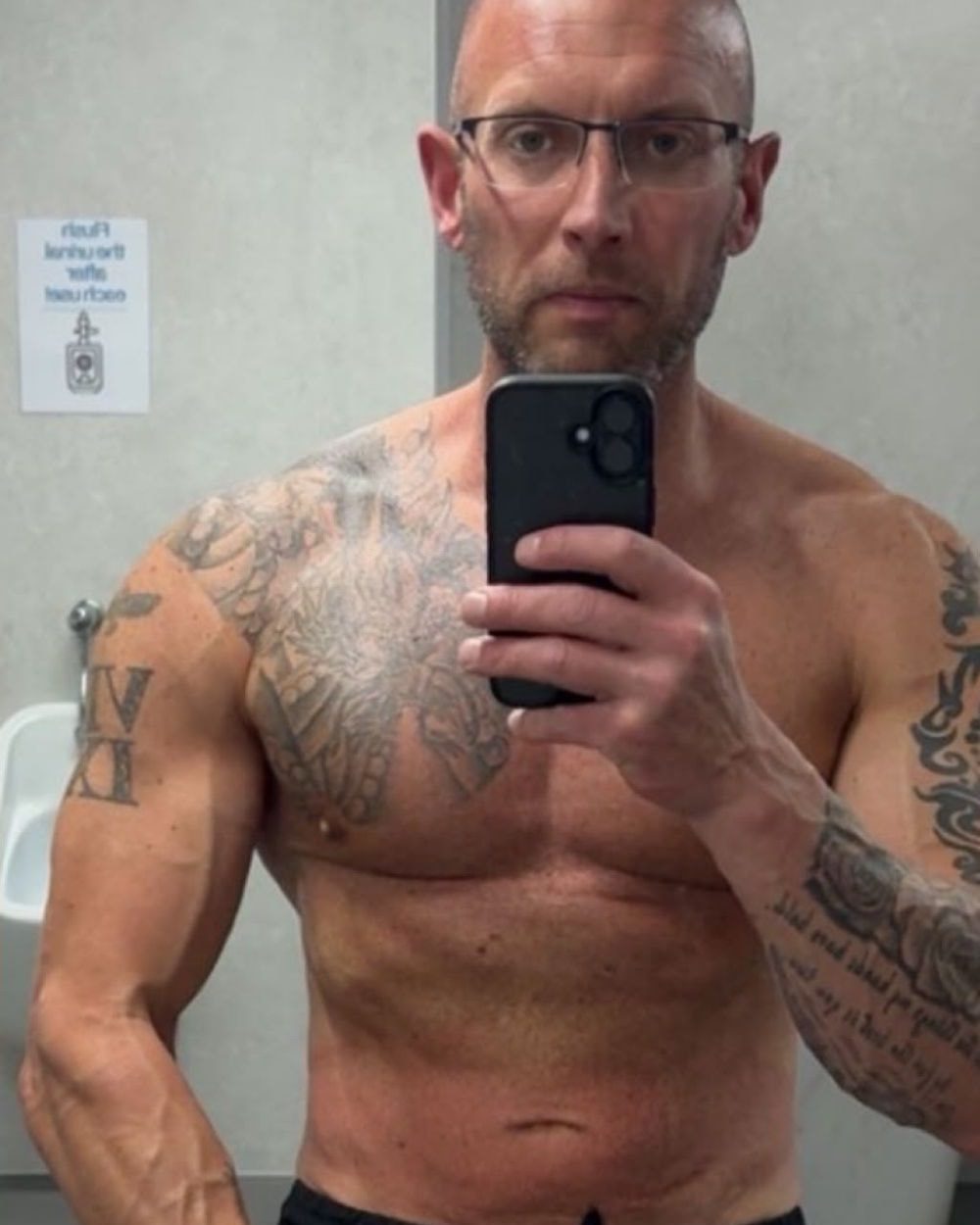 Client 3 after coaching: mirror selfie in the gym changing room, leaner midsection with more definition in the arms and chest