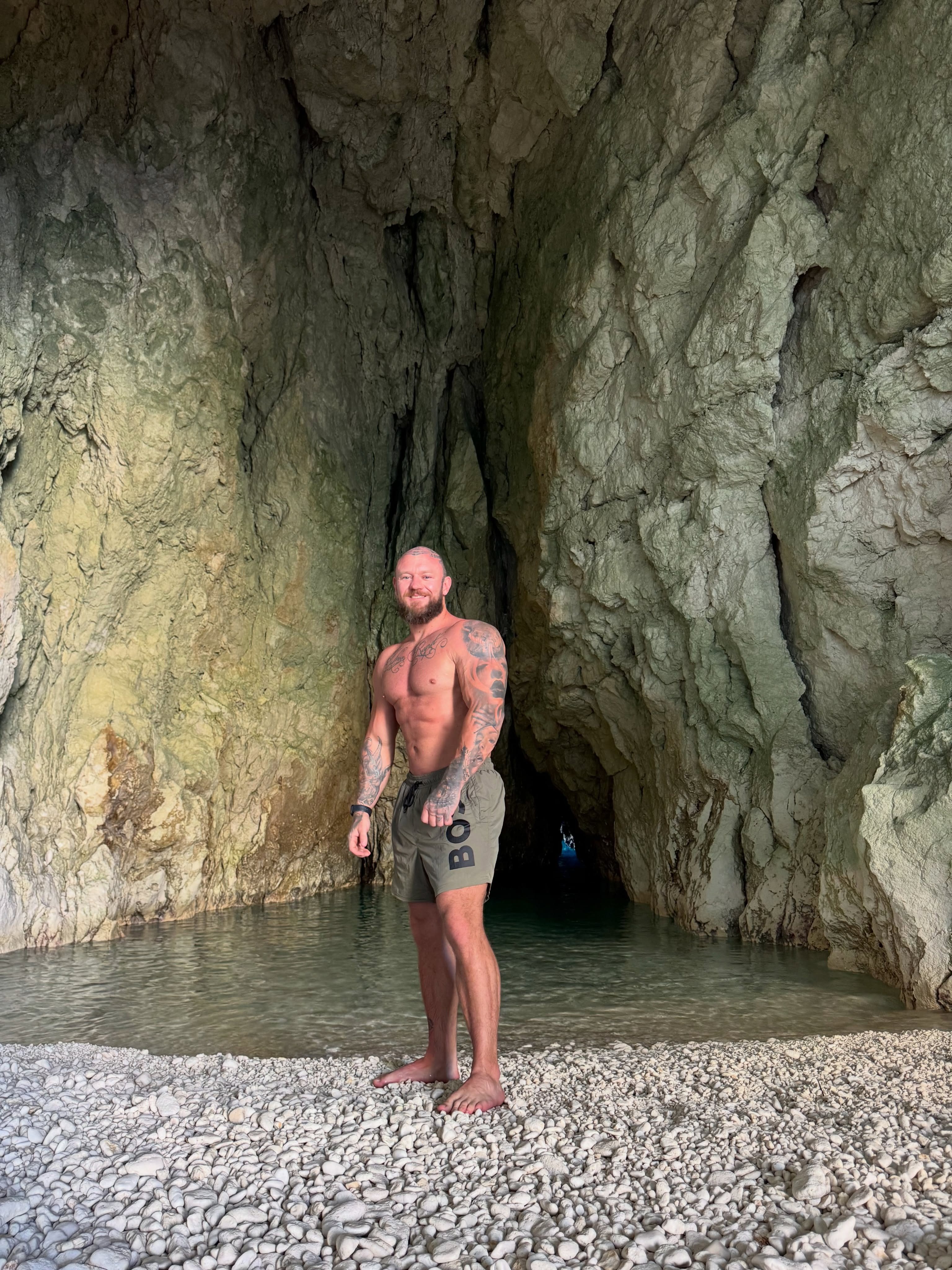 Dan, physique coach, standing in a sea cave